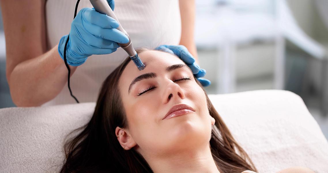 Person receiving a cosmetic facial skin treatment with a handheld device while resting on a treatment bed.