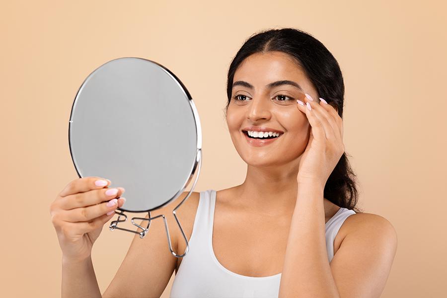Woman admiring her glowing, radiant skin in a mirror following a radiance-focused microneedling treatment at SVIT Aesthetics in Southlake Texas