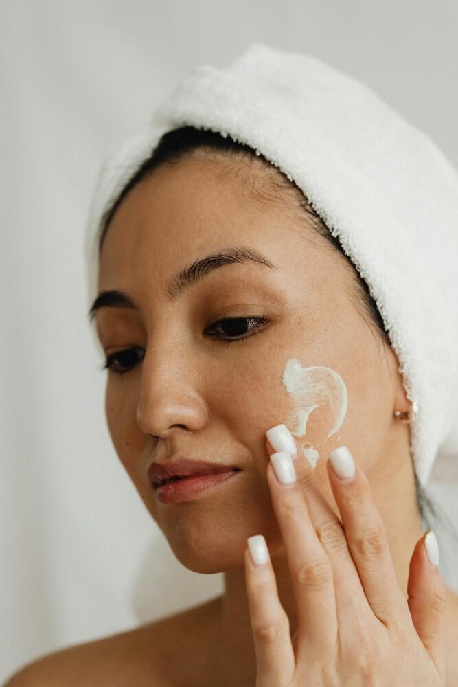 Woman applying hydrating skincare cream to her face for daily moisture maintenance.