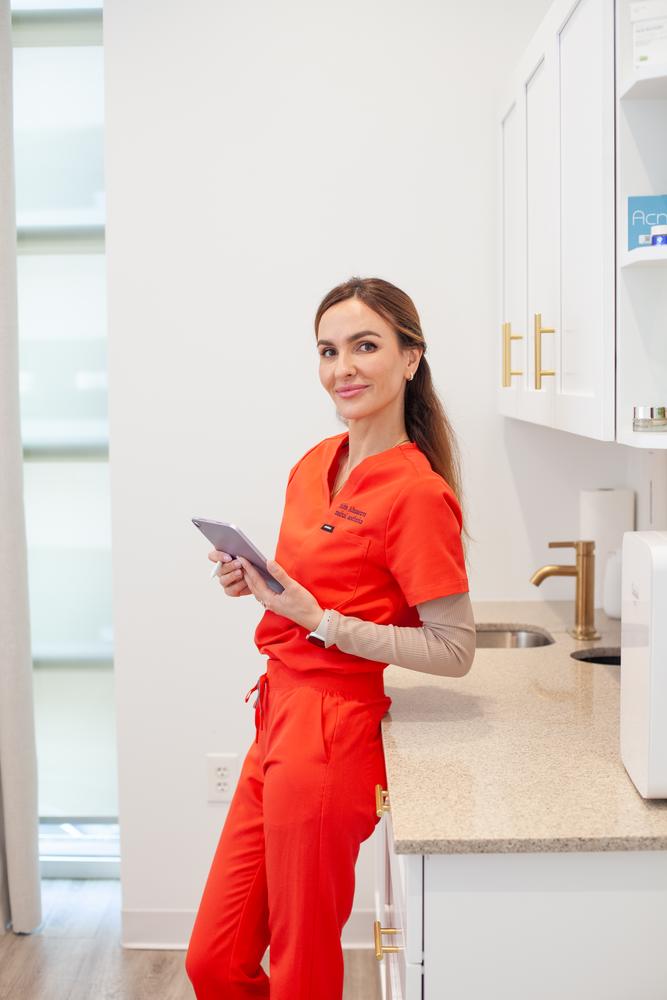 SVIT Aesthetics provider standing in a modern treatment space holding a tablet before a first aesthetic consultation in Southlake, TX.