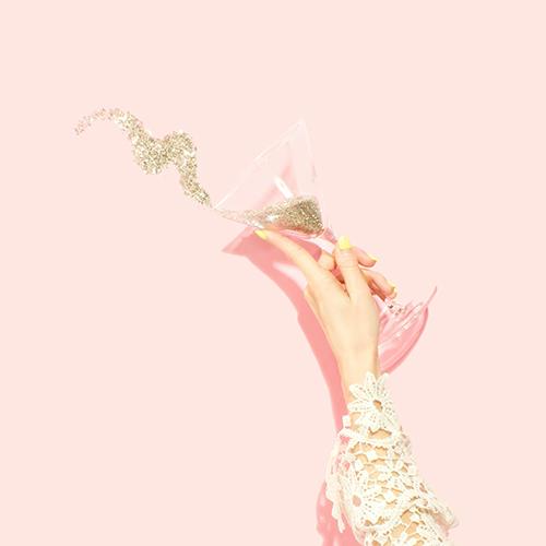Hand holding a celebratory glittered glass representing the members-only Birthday Facial at SVIT Aesthetics in Southlake